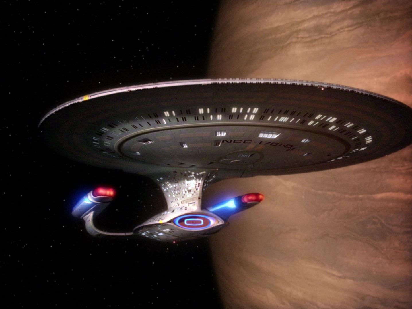 The Enterprise D, viewed from the front against a large orange planet in the background