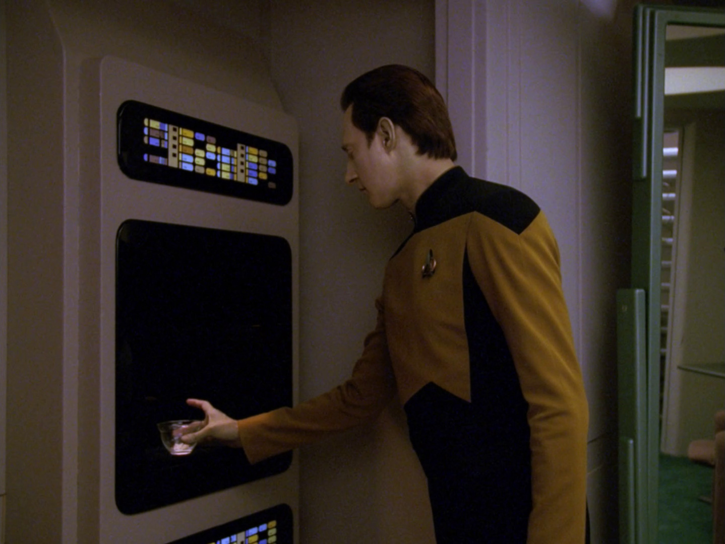 Commander Data takes a small glass bowl of water from the replicator
